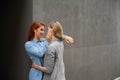 Passionate loving lesbian couple. Two beautiful young women hugging tenderly outdoors against a gray wall. LGBT commune