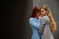 Passionate loving lesbian couple. Two beautiful young women hugging tenderly outdoors against a gray wall. LGBT commune