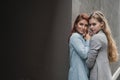 Passionate loving lesbian couple. Two beautiful young women hugging tenderly outdoors against a gray wall. LGBT commune