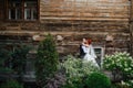 Passionate newly wed couple kissing lips in front of an old wooden house wall