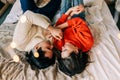 Passionate romantic couple spending home with garlands. Young woman and man are lying on bed in sweaters and hugging