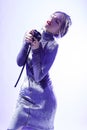 Passionate Singing Caucasian Female In Gray Reflective Dress Posing With Microphone Over White Background