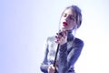 Passionate Singing Caucasian Female In Gray Reflective Dress Posing With Microphone Over White Background