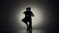 Passionate tango choreography elements performed by pair of ballroom dancers. Black silhouettes of man and woman moving