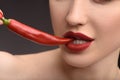 Passionate woman biting hot chili