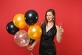 Passionate woman in black dress celebrating blinking holding glass of champagne air balloons isolated on red background Royalty Free Stock Photo