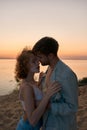 Passionate young couple getting undressed while going to make love, standing on the beach at sunset Royalty Free Stock Photo