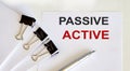 PASSIVE ACTIVE written on a white page with office tools