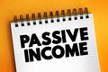 Passive income - regular earnings from a source other than an employer or contractor, text concept on notepad