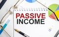 Passive Income Words on notepad and glasses with charts Royalty Free Stock Photo