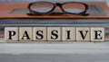 PASSIVE - word on wooden cubes on the background of a folder with documents and glasses