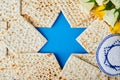 Passover celebration concept. Blue Star of David made from matzah, white and yellow roses, kippah and walnut on bluebackground.