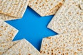 Passover celebration concept. Blue Star of David made from matzah, white and yellow roses, kippah and walnut on bluebackground.