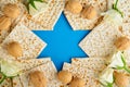 Passover celebration concept. Blue Star of David made from matzah, white and yellow roses, kippah and walnut on bluebackground.