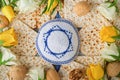 Passover celebration concept. Blue Star of David made from matzah, white and yellow roses, kippah and walnut on bluebackground