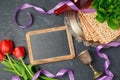 Passover holiday concept matzoh, chalkboard and tulip flowers on dark background. Royalty Free Stock Photo