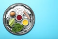 Passover Seder plate keara with symbolic meal on light blue background. Pesah celebration