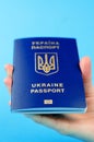 Passport of a citizen of Ukraine in a female hand on a blue background. Inscription in Ukrainian Ukraine Passport