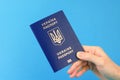 Passport of a citizen of Ukraine in a female hand on a blue background. Inscription in Ukrainian Ukraine Passport