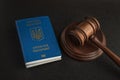 Passport of a citizen of Ukraine and a judicial hammer on a black background. Legal immigration. Obtain citizenship