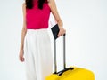 Passport with flight ticket in women`s hand in pink sleeveless and white trousers while she holding a suitcase. Royalty Free Stock Photo