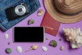 Passport, Jeans, Camera, Hat, Smartphone, Seashells on Lilac Background. Top View Travel Concept Mock up.