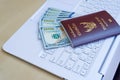 passport with US dollar on white keyborad on wood desk, travel c