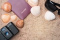 Passport, vintage camera, sunglasses and seashells on golden beach sand