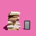 Past and present reading books inspired concept. E book reader stand alone beside the many books against purple background Royalty Free Stock Photo