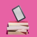 Past and present reading books inspired concept. E book reader stand up on the many books against purple background Royalty Free Stock Photo