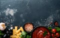 Pasta background. Pasta rigatoni, tomato ketchup sauce, olive oil, spices, parsley, and fresh tomatoes on a dark slate, stone or