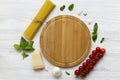 Pasta background. Spaghetti with tomatoes, cheese parmesan and basil, wooden board in the center