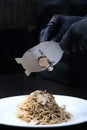 Pasta with black truffle . The chef slices the truffles thin . Unrecognizable person. Photo on a black background. Vertical photo
