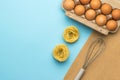 Pasta, a box of eggs and a whisk for whipping on a blue background Royalty Free Stock Photo
