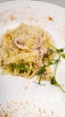 Pasta carbonara with ham and cheese. Garnished with pea sprouts. In a white plate Royalty Free Stock Photo