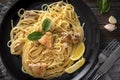 Pasta    with chicken fillet, lemon slices, garlic, greens, spinach,  napkin, fork, knife on a black plate on  dark ,  close up, Royalty Free Stock Photo