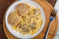 Pasta in a creamy sauce with mushrooms and chicken meatballs in a beige plate on a wooden table on a round stand with a fork Royalty Free Stock Photo