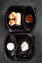 Pasta with cuttlefish ink and rolls of rice paper with vegetables in eco boxes. on a black background