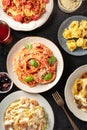 Pasta dishes variety. Pastas with meat, vegetables, seafood and mushrooms, with ravioli, grated Parmesan cheese, and