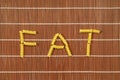 Pasta elements forming word FAT on brown table set Royalty Free Stock Photo