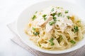 Pasta fettuccine alfredo with chicken, parmesan and parsley on white background close up