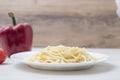 Pasta with gralic and chili. Hand with tongs move spaghetti with butter to a white plate on wood background