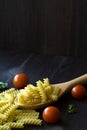 Italian pasta and ingredients. Fusilli pasta with cherry tomatoes on wooden table Royalty Free Stock Photo