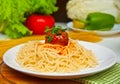 Pasta with meat balls in a tomato sauce on the white plate with fresh vegetables on the background Royalty Free Stock Photo