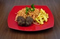 Pasta, meatballs and potatoes on a red plate on the table