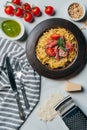 pasta with mint leaves jamon and cherry tomatoes covered by grated parmesan on plate at marble table with kitchen towel knife Royalty Free Stock Photo