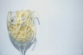 Pasta noodles in a wine glass, spilling out over the top.