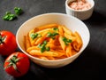 Pasta Penne in tomato sauce Pomodoro, garnished green basil leaves on black table. Traditional italian food Royalty Free Stock Photo