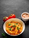 Pasta Penne in tomato sauce Pomodoro, garnished green basil leaves on black table. Traditional italian food. Copy space Royalty Free Stock Photo