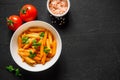 Pasta Penne in tomato sauce Pomodoro, garnished green basil leaves on black table. Traditional italian food. Top view Royalty Free Stock Photo